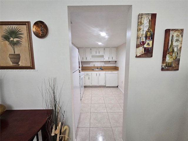 kitchen with dishwasher, backsplash, sink, light tile patterned floors, and white cabinetry