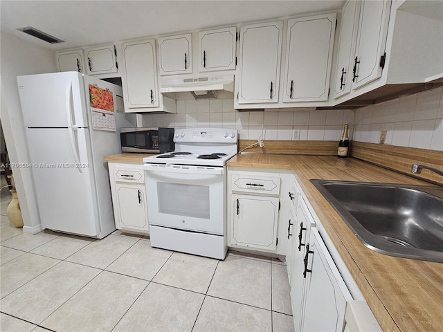 kitchen featuring tasteful backsplash, white appliances, sink, light tile patterned floors, and white cabinets