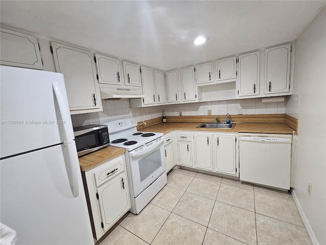 kitchen with tasteful backsplash, white appliances, extractor fan, sink, and white cabinetry