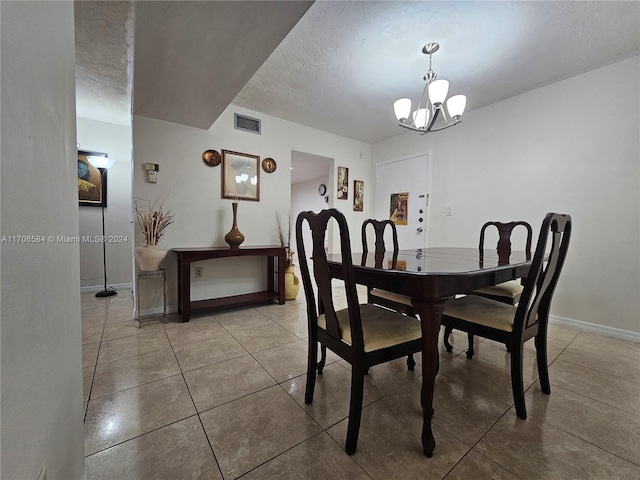 tiled dining room with a notable chandelier and a textured ceiling