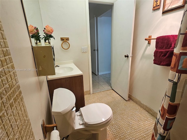 bathroom with toilet, vanity, and tile patterned floors