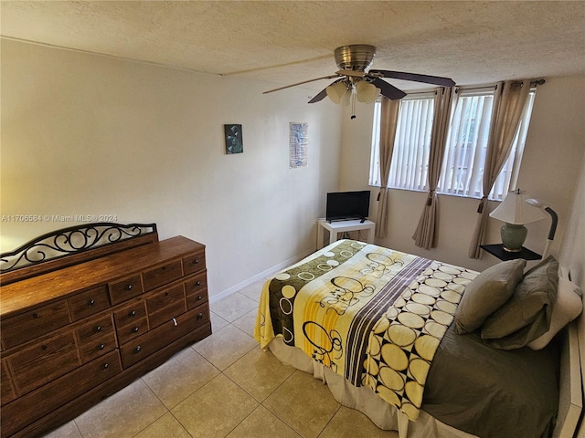 bedroom with ceiling fan, light tile patterned floors, and a textured ceiling