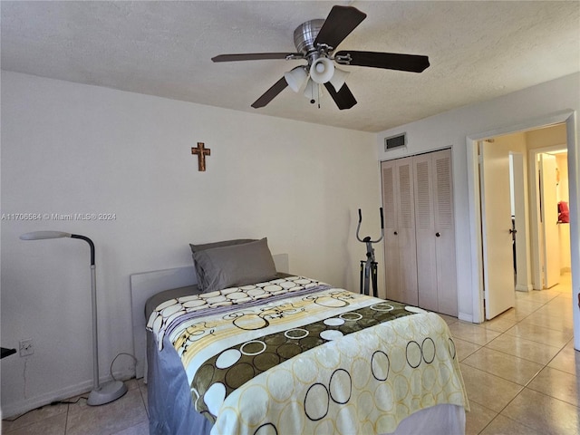 bedroom with light tile patterned flooring, a textured ceiling, a closet, and ceiling fan