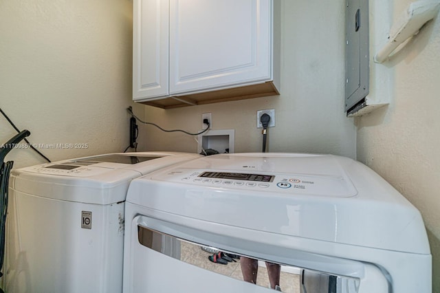 washroom with cabinets, washing machine and dryer, and electric panel