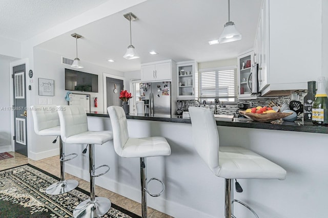 kitchen featuring a kitchen bar, white cabinetry, decorative light fixtures, and appliances with stainless steel finishes