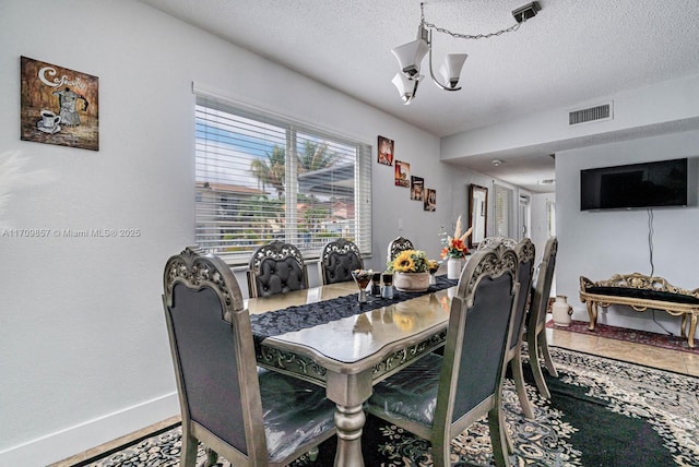 dining room featuring tile patterned floors, a textured ceiling, and an inviting chandelier