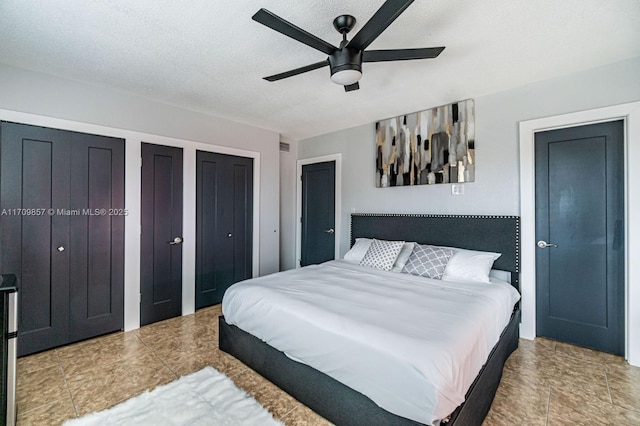 bedroom with ceiling fan, a textured ceiling, and multiple closets