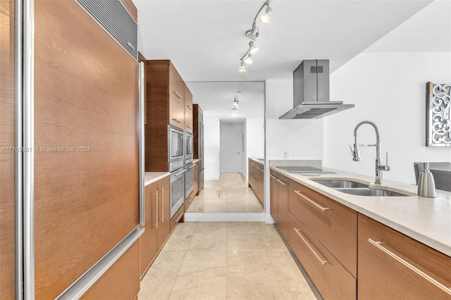 kitchen featuring black electric stovetop, paneled built in fridge, wall chimney range hood, and sink