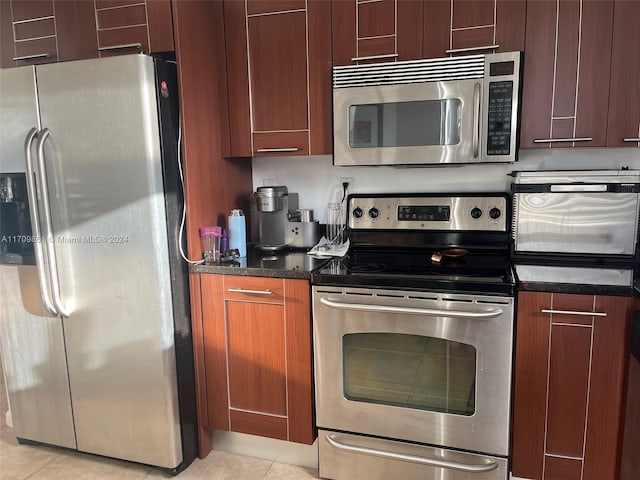 kitchen featuring dark stone counters, light tile patterned flooring, and stainless steel appliances