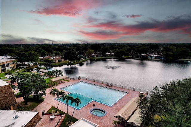 pool at dusk featuring a water view