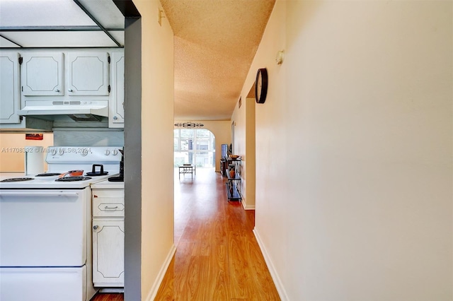 kitchen with a textured ceiling, white cabinetry, light hardwood / wood-style flooring, and electric stove