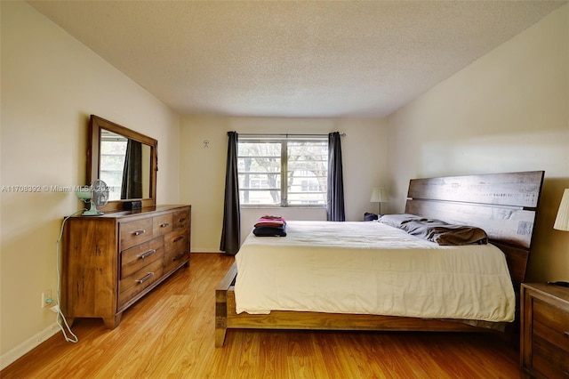 bedroom with light wood-type flooring, a textured ceiling, and multiple windows