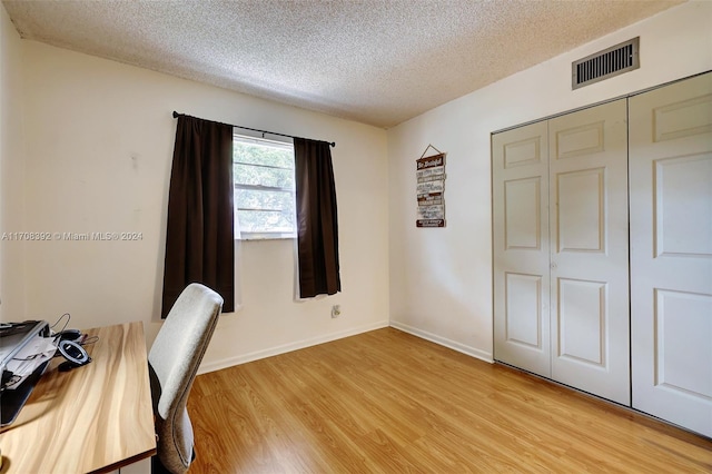 unfurnished office with a textured ceiling and light wood-type flooring