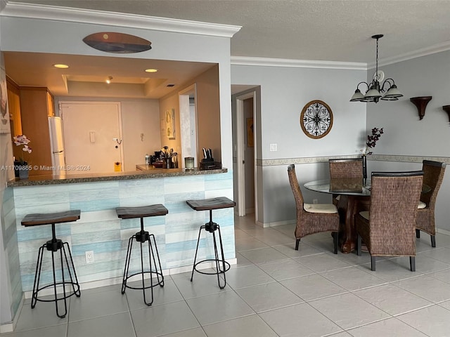 kitchen featuring decorative light fixtures, white refrigerator, crown molding, and a chandelier