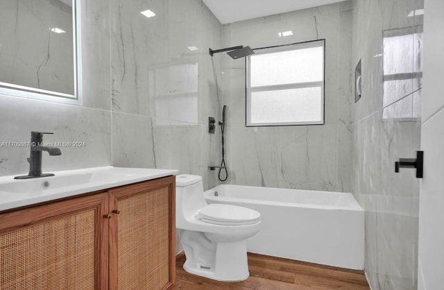 full bathroom featuring vanity, wood-type flooring, tile walls, toilet, and tiled shower / bath