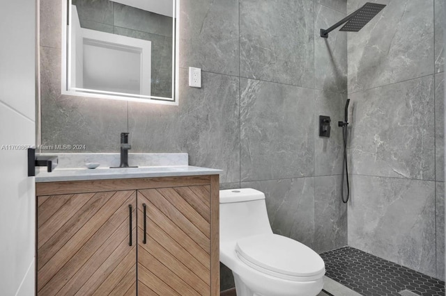 bathroom with tiled shower, vanity, tile walls, and toilet