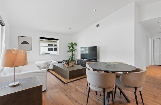 living room with high vaulted ceiling and light hardwood / wood-style flooring