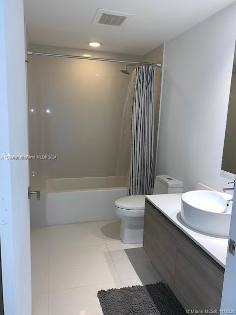 full bathroom featuring tile patterned floors, vanity, shower / bath combination with curtain, and toilet