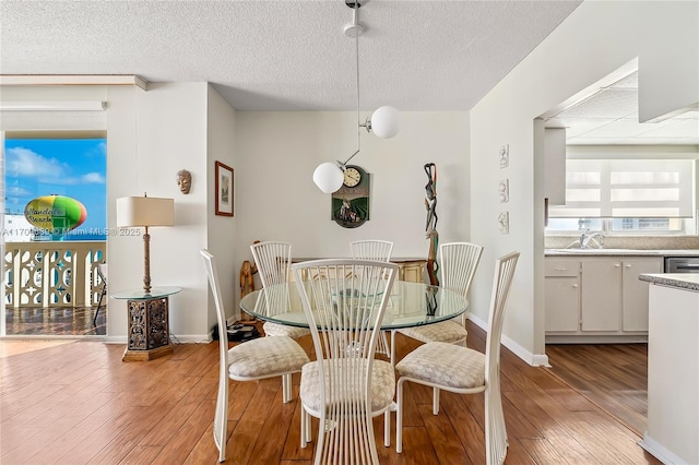 dining space featuring sink, a textured ceiling, and light wood-type flooring