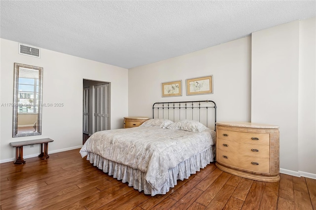 bedroom featuring dark hardwood / wood-style flooring and a textured ceiling