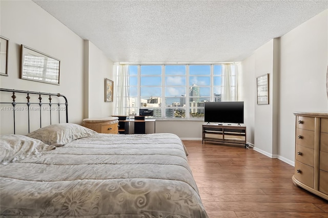 bedroom with a textured ceiling and dark hardwood / wood-style flooring