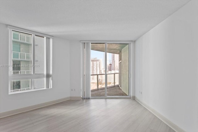 spare room featuring a textured ceiling, light wood-type flooring, and expansive windows