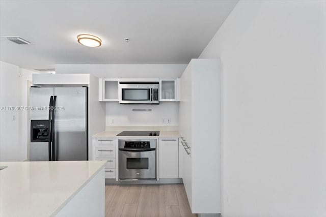 kitchen featuring white cabinetry, light wood-type flooring, and appliances with stainless steel finishes