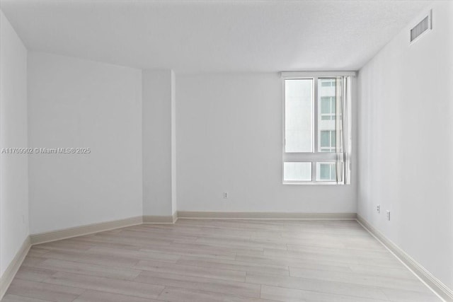 unfurnished room featuring light wood-type flooring and a textured ceiling