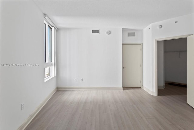 interior space with a walk in closet, light wood-type flooring, and a closet