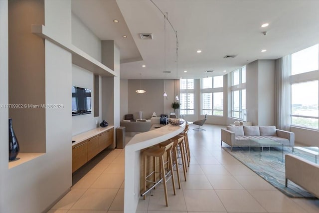 kitchen with decorative light fixtures, a healthy amount of sunlight, light tile patterned floors, and a breakfast bar area