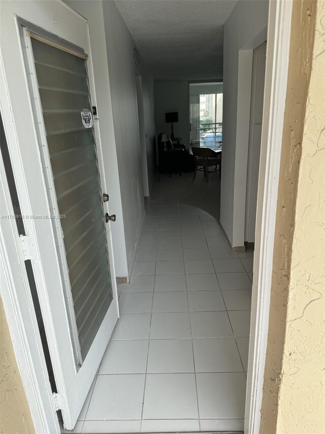 hall featuring light tile patterned floors and a textured ceiling