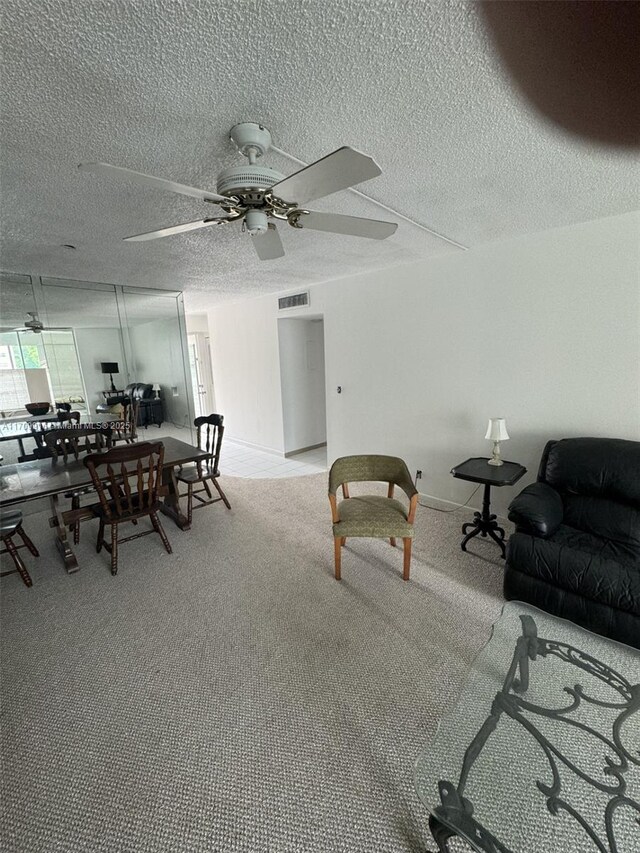 carpeted living room featuring ceiling fan and a textured ceiling