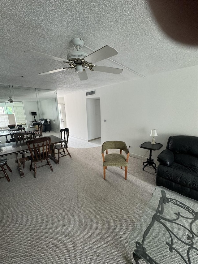 interior space featuring visible vents, light carpet, ceiling fan, a textured ceiling, and baseboards