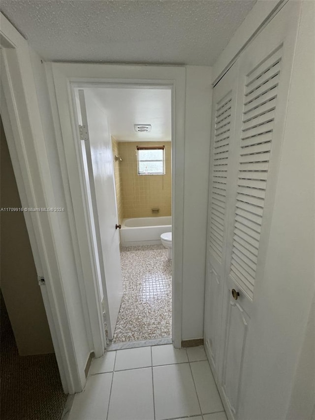 hall featuring light tile patterned floors and a textured ceiling