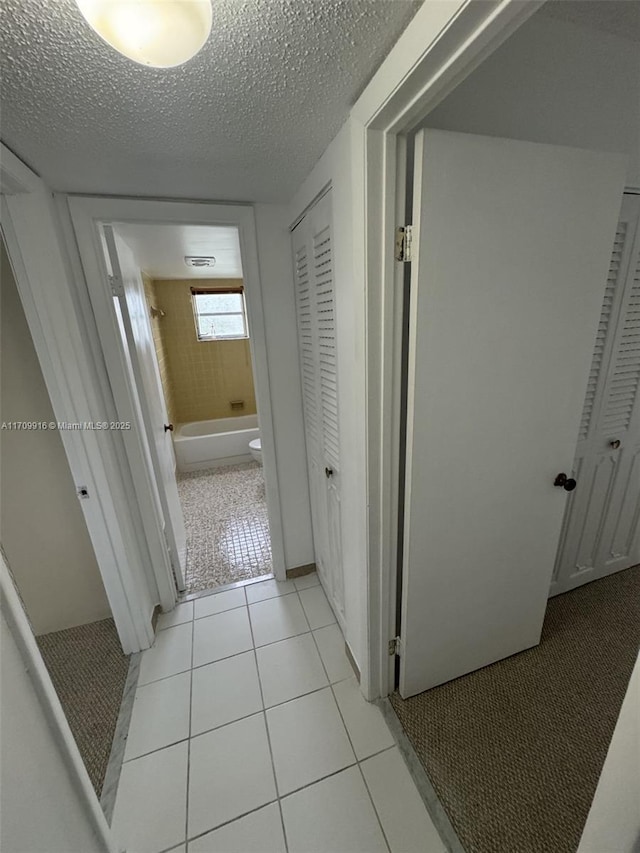 hallway featuring light tile patterned floors and a textured ceiling