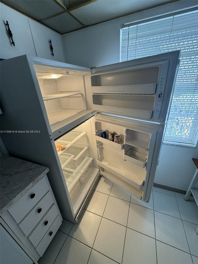 kitchen featuring light tile patterned floors, fridge, and a drop ceiling