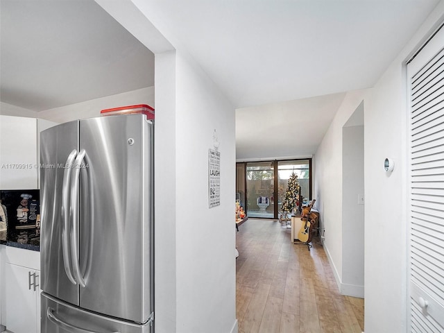 kitchen with white cabinets, stainless steel refrigerator, and light hardwood / wood-style flooring