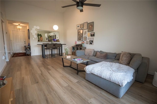 living room featuring ceiling fan, high vaulted ceiling, and light hardwood / wood-style floors