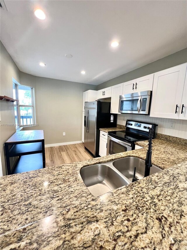 kitchen featuring range, dishwasher, white cabinets, and sink