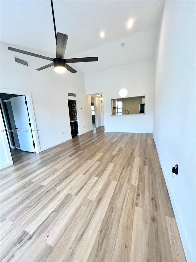 unfurnished living room featuring ceiling fan, vaulted ceiling, and light hardwood / wood-style flooring