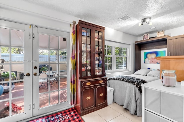 bedroom featuring light tile patterned floors, a textured ceiling, and french doors