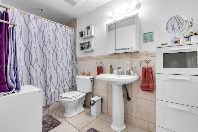 bathroom featuring tile patterned flooring, toilet, tile walls, and walk in shower