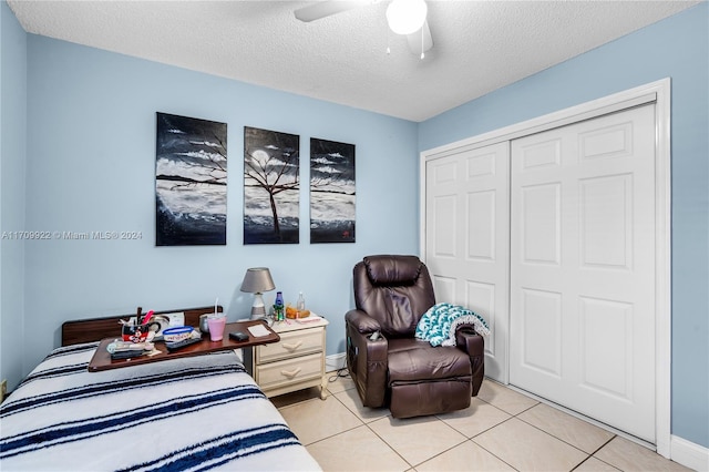 bedroom with ceiling fan, light tile patterned flooring, a textured ceiling, and a closet