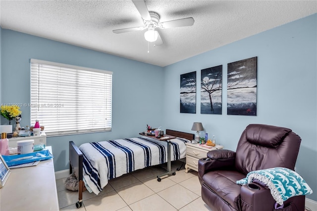 bedroom featuring ceiling fan, light tile patterned floors, and a textured ceiling