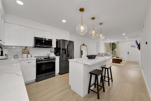 kitchen with backsplash, hanging light fixtures, light stone countertops, white cabinetry, and stainless steel appliances