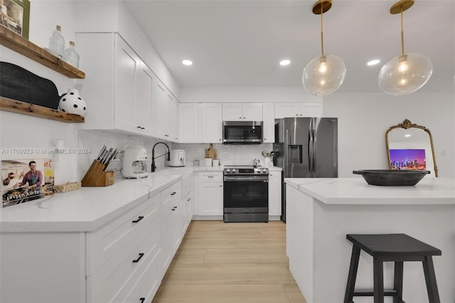 kitchen featuring decorative backsplash, appliances with stainless steel finishes, light stone counters, white cabinetry, and hanging light fixtures