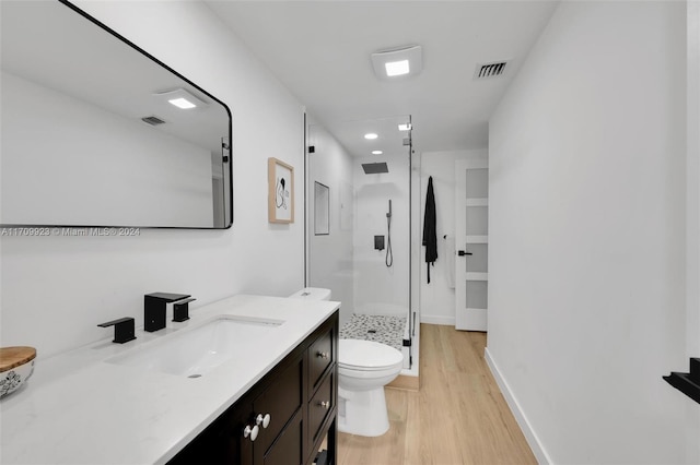 bathroom with hardwood / wood-style floors, vanity, toilet, and a shower with shower door