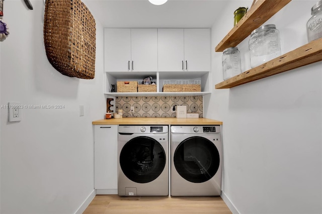 clothes washing area with cabinets, independent washer and dryer, and light hardwood / wood-style flooring