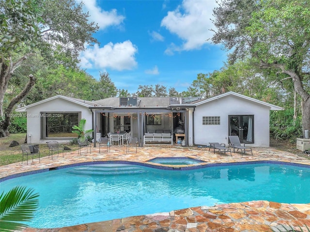 rear view of house with a swimming pool with hot tub and a patio area