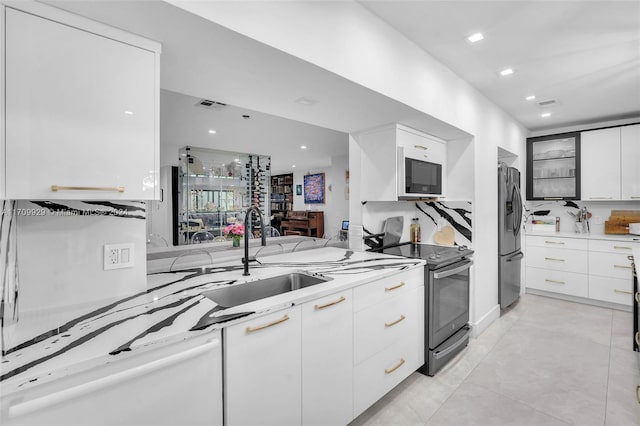 kitchen featuring light stone countertops, kitchen peninsula, stainless steel appliances, sink, and white cabinetry